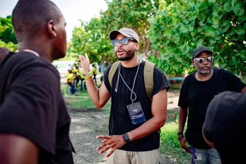 Swan Badol, badge d'organisateur au cou, en train de briefer trois personnes sur le site d'un festival.