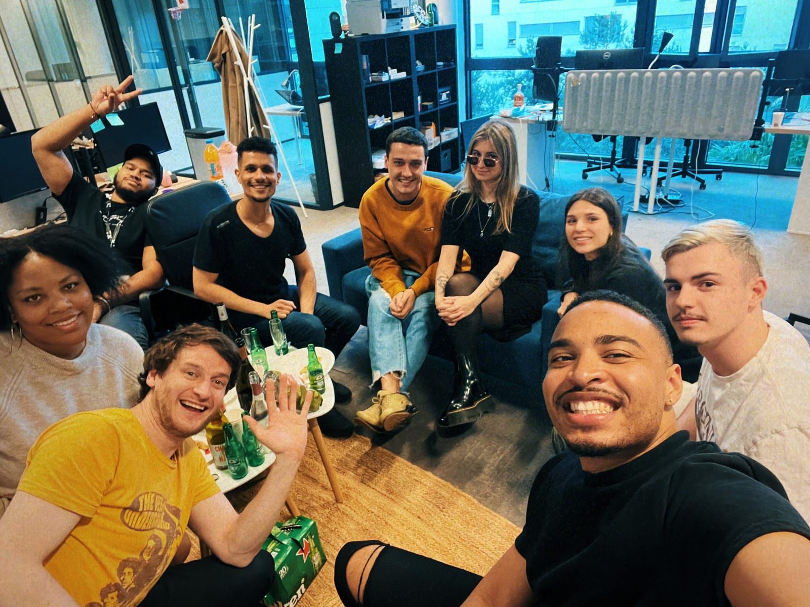 Une dizaine de personnes de l'agence réunies dans l'open space en fin de journée, autour d'une table basse.